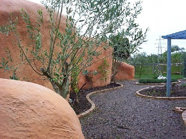 Wie eine große Skulptur oder ein Steinhaus in Arizona mutet die organische Wand an, mehr als nur ein Sichtschutz.
	
© Chug's Strawbale World